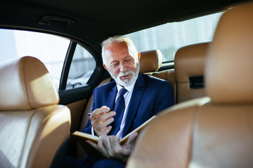 Senior business man sitting in his limousine. Business concept. Back light.