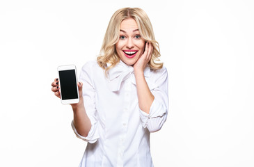 Gorgeous excited woman showing blank screen mobile phone over white background, celebrating victory...