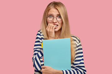 People and university life concept. Nervous worried pleasant looking student bites finger nails...
