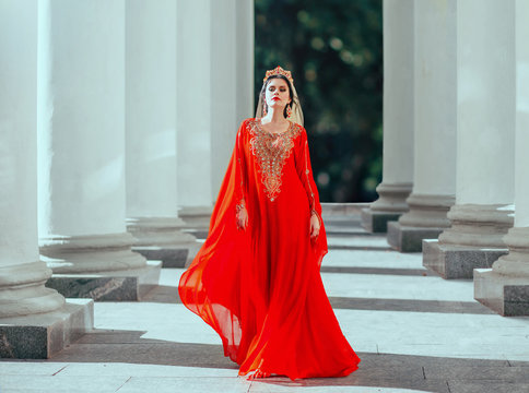 Gorgeous proud dark-haired confident haseki sexy queen roksolana in amazing expensive luxury red long flying dress with gold, beads and precious stones, wearing crown and earrings. art fantasy photo