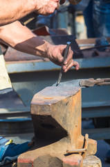 blacksmith performs the forging of hot glowing metal on the anvil