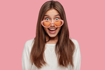 Beauty, fashion concept. Joyful smiling dark haired woman wears sunglasses and white jacket, being...