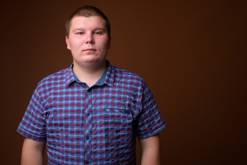 Fototapeta premium Studio shot of overweight young man against brown background