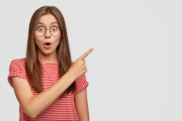 Indoor shot of stupefied emotive brunette woman has shocked expression, stares with bugged eyes,...