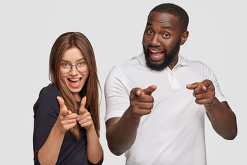 Positive girl and guy of different races make finger gun gesture, smile positively, express their...