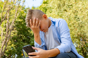 childhood, augmented reality, technology and people concept - boy with upset face looks into the smartphone outdoors at summer