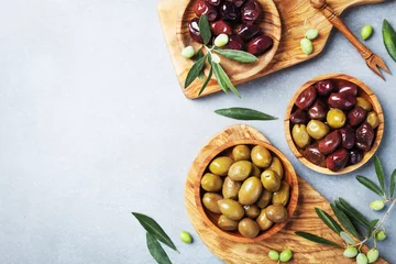Poster Marinated olives in bowls on kitchen board from olive wood top view. © juliasudnitskaya