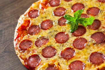Pepperoni Pizza with Mozzarella cheese, salami, Tomato sauce, pepper, Spices and Fresh Basil. Italian pizza on wooden background