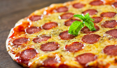 Pepperoni Pizza with Mozzarella cheese, salami, Tomato sauce, pepper, Spices and Fresh Basil. Italian pizza on wooden background