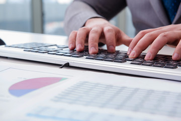 Finance professional working on keyboard with reports