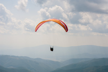 One paraglider fly over a mountain valley on a sunny summer day. Paragliding in the Carpathians in the summer.