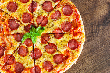 Pepperoni Pizza with Mozzarella cheese, salami, Tomato sauce, pepper, Spices and Fresh Basil. Italian pizza on wooden background