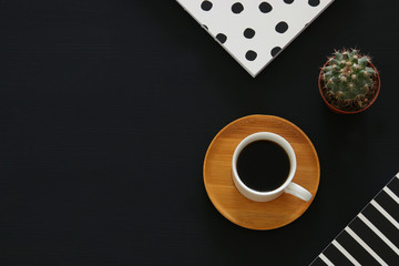 image of coffee cup and notebook over black background. Top view.