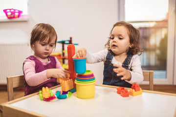 Children toddlers girls play toys at home, kindergarten or nursery.