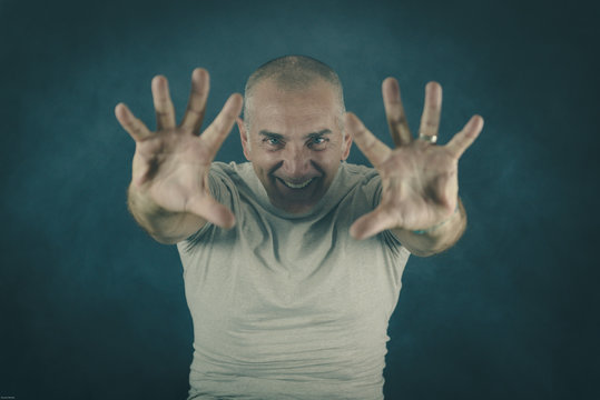 A man, 50Y old, is showing palms toward the observer. Black background, smoke.