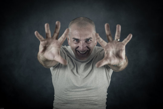 A man, 50Y old, is showing palms toward the observer. Black background, smoke.