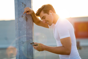 Sportive young man in the city with smartphone
