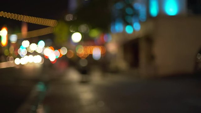 Blurred background plate of city street sidewalk at night with bokeh headlights