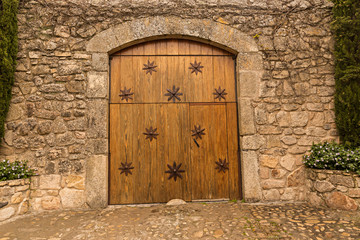 Fototapeta na wymiar Puerta de madera con adornos de estrellas y fachada de piedra antigua.