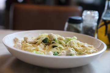 alfredo spaghetti broccoli chicken white sauce in restaurant background