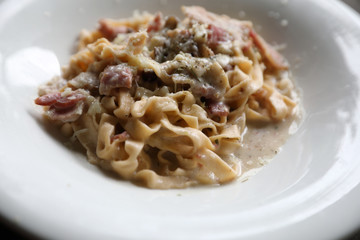 Pasta white sauce with bacon and mushroom on wood background in mystic light