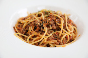 spaghetti Bolognese with minced beef and tomato sauce garnished with parmesan cheese and basil , Italian food