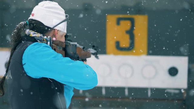 A professional biathlonist shoots at targets and continues running on a track.