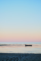 Small fishing boat in bay at dusk after sunset