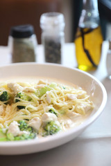 alfredo spaghetti broccoli chicken white sauce in restaurant background
