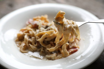 Pasta white sauce with bacon and mushroom on wood background in mystic light