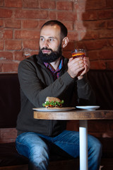businessman male brunette beard glass hold cafe office house loft brave bearded hipster mulled wine close up hamburger