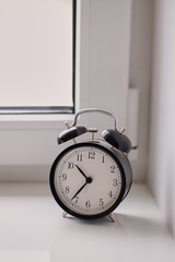 old mechanical alarm clock is on the windowsill