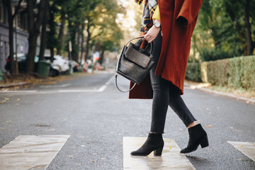 street style, attractive woman wearing a brown oversized coat,black jeans, ankle boots and a croc effect tote bag. fashion outfit perfect for sunny autumn.