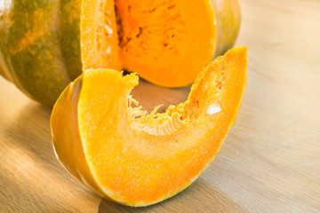 Sliced orange ripe pumpkin with slice on wooden desk