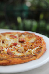 Pizza with crispy bacon onion on outdoor table