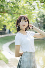 Fototapeta premium portrait of asian girl with white shirt and skirt looking in outdoor nature vintage film style