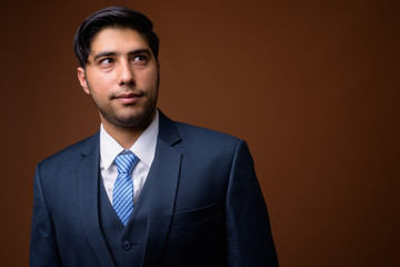 Young handsome Iranian businessman against brown background