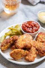 Fried crispy chicken nuggets with ketchup and pickles