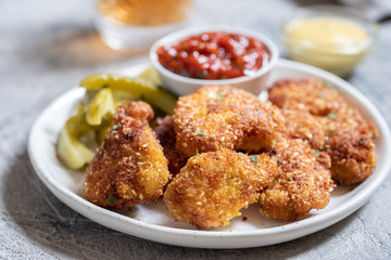 Fried crispy chicken nuggets with ketchup and pickles