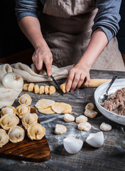 Hands of the girl prepare dumplings on a wooden table