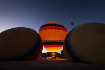 Obraz premium Hot air balloon illuminated between other two still sleeping with beautiful blue sky in background