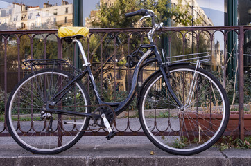 Fototapeta na wymiar A bicycle parked along a sidewalk in the streets of Paris with a reflection of the Parisian buildings 