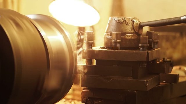 Working process at the machine at engineering plant. Working process of production of a metal pig on the machine. During friction there is a smoke.