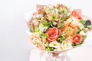 beautiful spring bouquet. flowers arrangement with various of colors in glass vase on pink table. bright room, white wall. copy space
