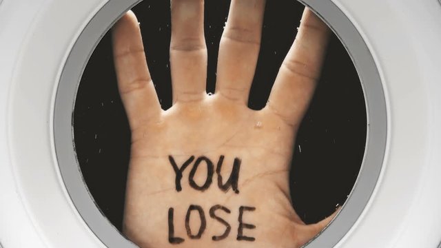 hand with the inscription on the palm: you lose, appears in the illuminator from the dark depths, close-up