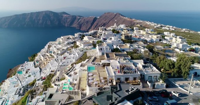 Village of Santorini under the blue sky. We can see the traditional white houses and villas of the island near a cliff - aerial view with a drone - Travel concept