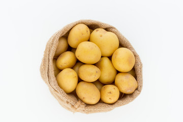 Sack of fresh raw potatoes on wooden background, top view