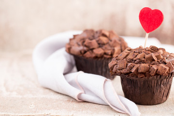 Homemade chocolate muffins with heart, vintage background.