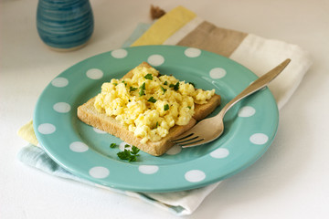 Simple classic breakfast of bread toast and scrambled eggs with parsley.