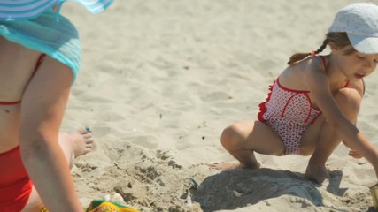 Woman and child playing with sand on beach